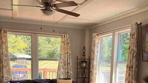 A living room with a ceiling fan, a sofa, a coffee table, and a fireplace. - Cozy cabin with riverfront location, fire pit and peaceful surroundings (Ellijay)