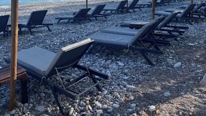 A beachside area with sun loungers and thatched umbrellas, a pebble beach, and a clear view of the sea. - Matteo Villa Limassol Cyprus (Limassol)