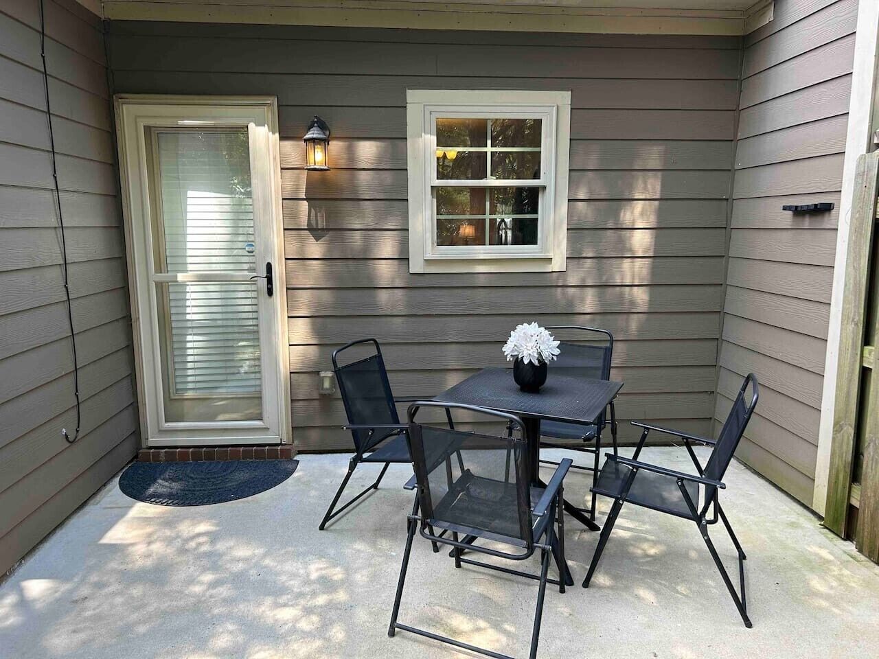 A patio with a table and chairs, a door, and a window.