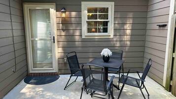 A patio with a table and chairs, a door, and a window.