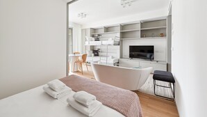 Una habitación de hotel moderna con una cama grande, un escritorio, un televisor y un baño.
