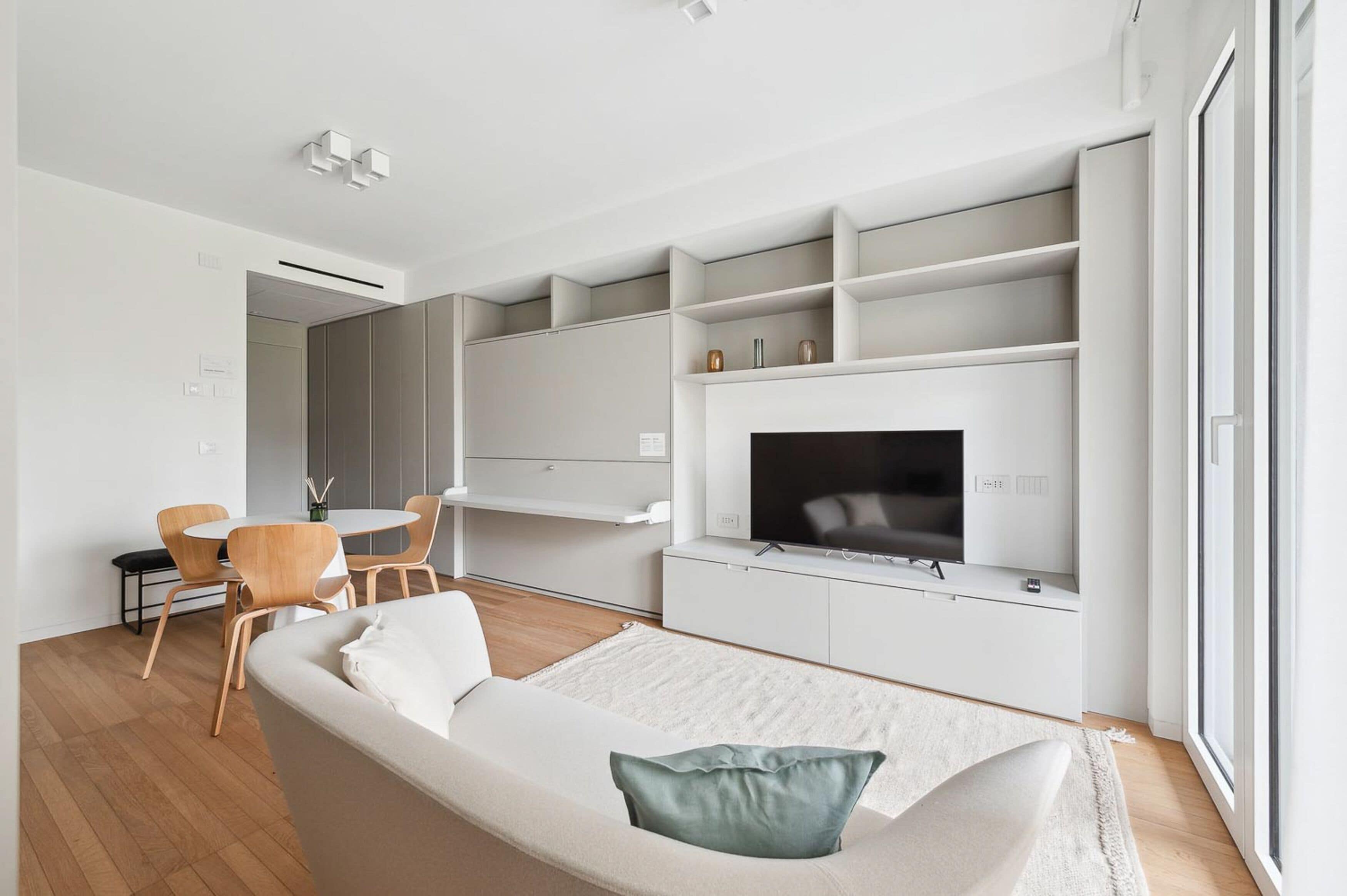 A modern living room with a sofa, a TV, and built-in shelves.