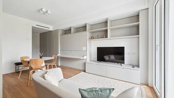 Una sala de estar moderna con un sofá, un televisor y estanterías empotradas.