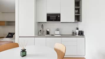 A modern kitchen with white cabinetry, a built-in microwave, and a coffee maker.