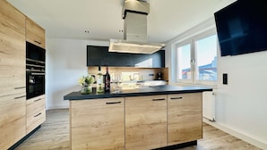 Una cocina moderna con una isla central, horno empotrado y un ventanal que proporciona luz natural.