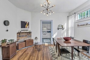 Enjoy meals in this dining area with a wooden table and chairs, a chandelier, and a kitchen nearby.