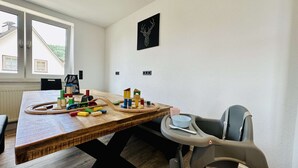 A dining area with a wooden table, colorful wooden blocks, and a child's high chair. - B&W Apartments - 1. Etage Wohnung (Morschen)