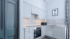Et moderne køkken med hvide skabe, en mikroovn, ovn og et mønstret backsplash.