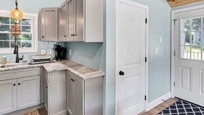 A kitchen with white cabinets, a wooden ceiling, and a window.