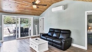 A spacious living room with a black leather sofa, a white coffee table, and a ceiling fan.