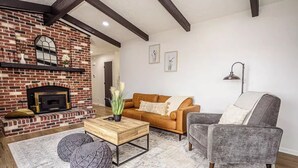 A living room with a brick fireplace, a wooden coffee table, a gray armchair, and a brown sofa.