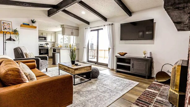 A spacious living area with a sofa, coffee table, and a TV mounted on the wall.