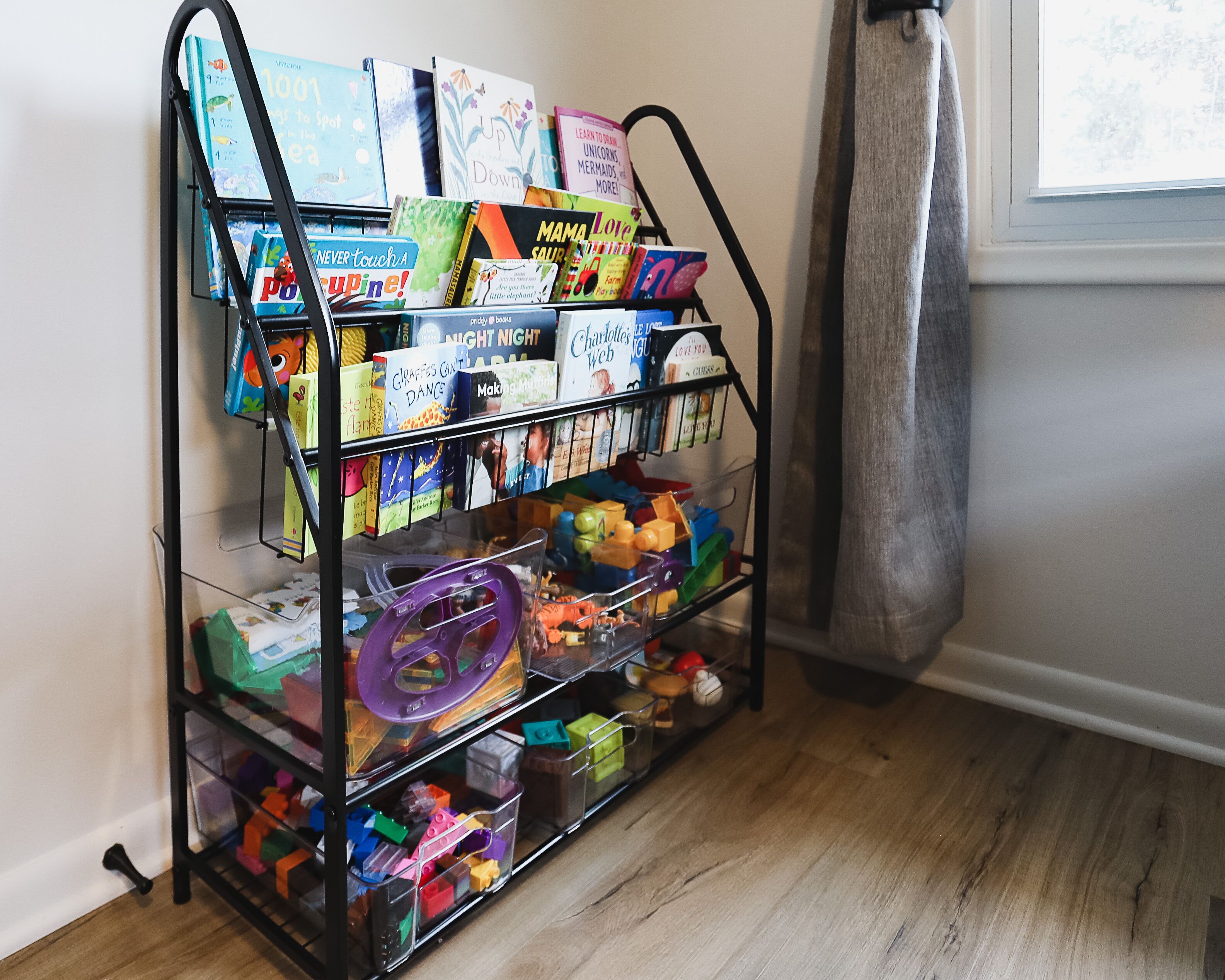 Ein Metallregal mit Kinderbüchern und Spielzeug.