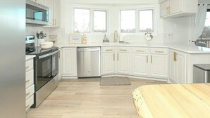 A modern kitchen with white cabinetry, a stainless steel oven, and a dishwasher.