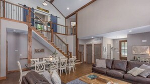A spacious living room with a staircase, a dining area, and a large brown leather sofa.