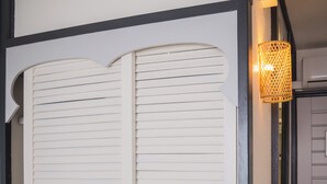 Une pièce avec une porte blanche à lattes horizontales, une petite fenêtre à cadre blanc et un luminaire fixé au mur.