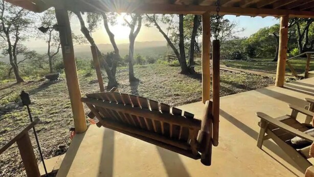 A wooden swing under a covered area with a view of trees and a distant landscape. - Gorgeous Views and only 13 mi to Lost Maples SNA, 22 mi to Garner State Park! (Utopia)