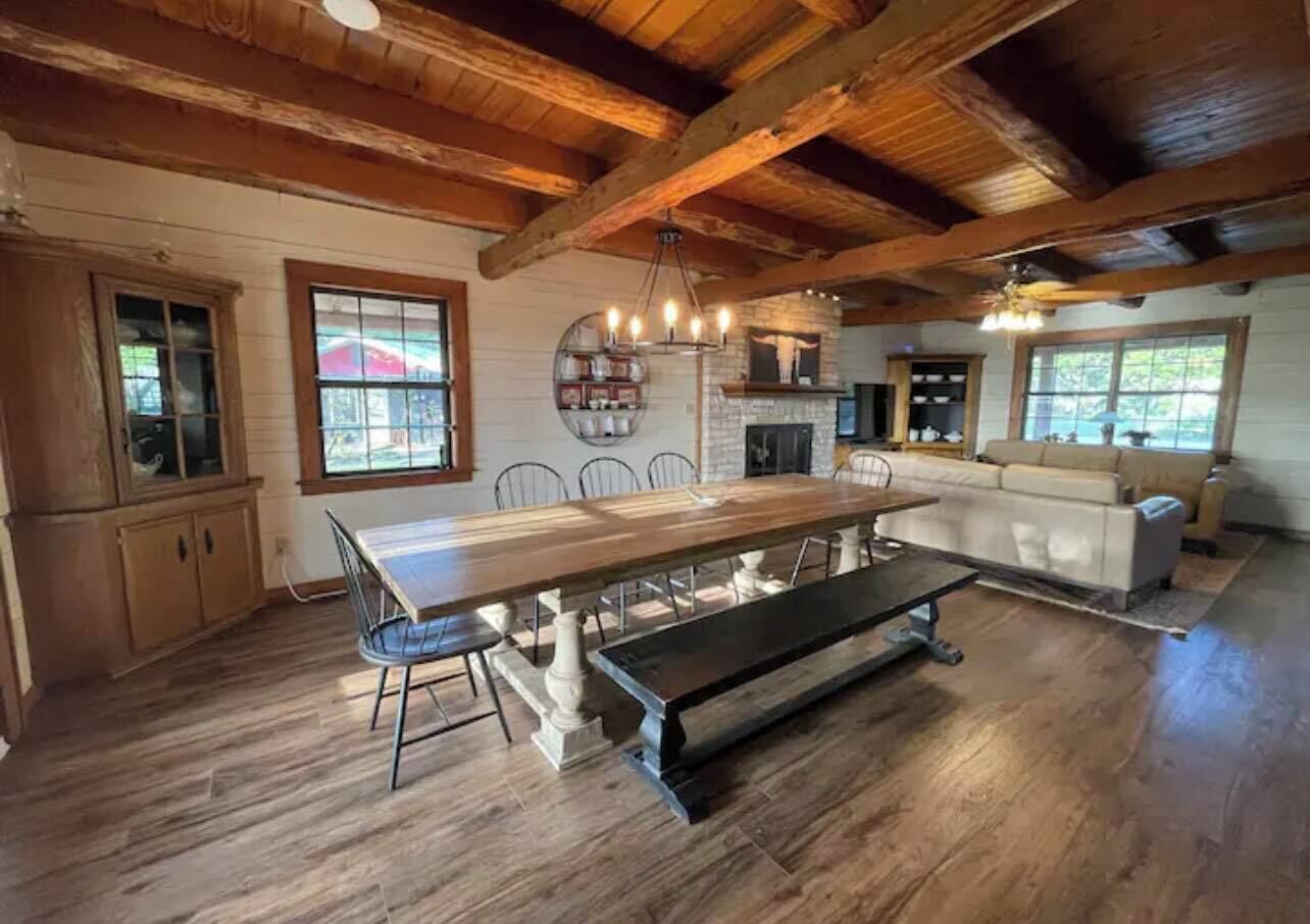 Une cuisine spacieuse avec une grande table en bois, des placards intégrés et une cheminée en pierre.