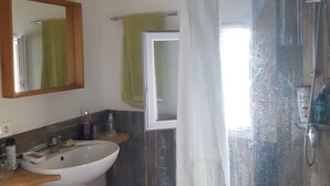 A bathroom with a sink, mirror, shower, and a towel hanging on the wall. - Location Maison de Village, vue Exceptionnelle (Grambois)