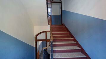 Eine Treppe mit Holzhandläufen und roten Stufen, die zu einer oberen Etage führt.