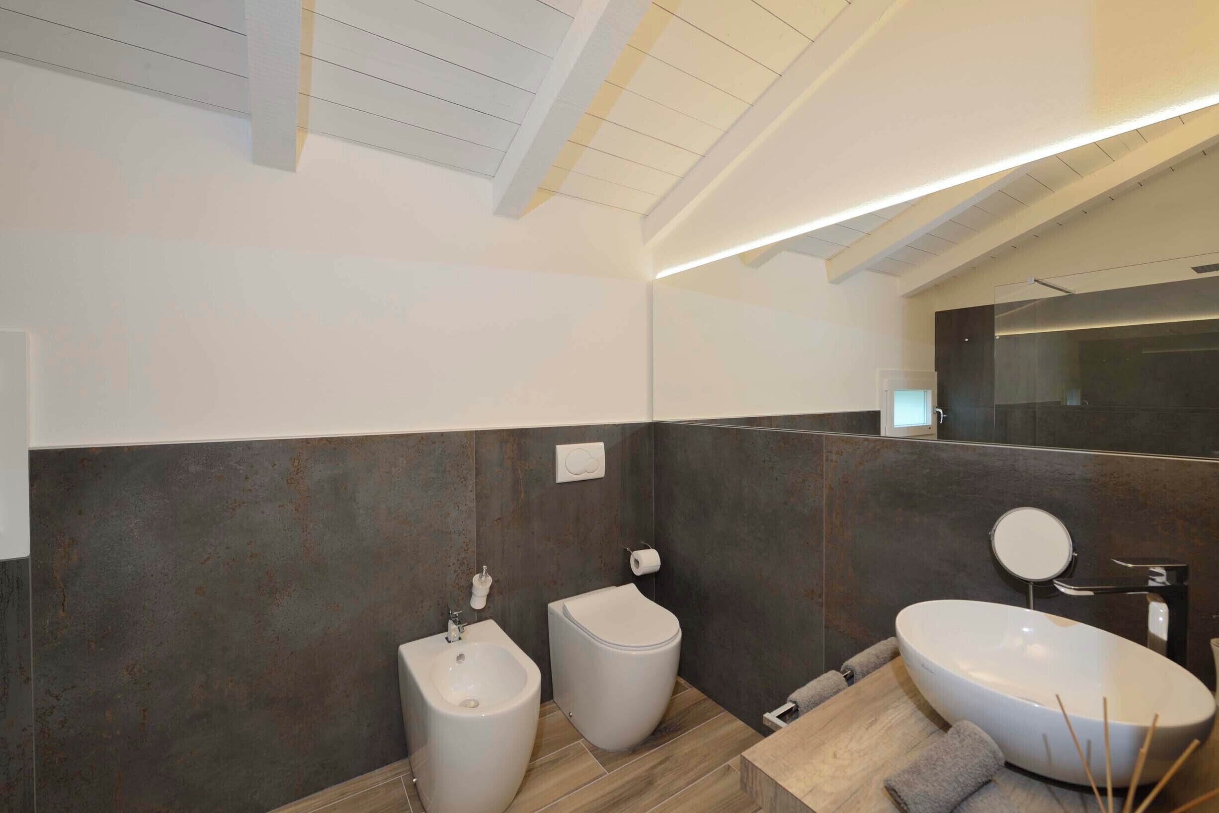 A modern bathroom with a bidet, toilet, and a large sink.