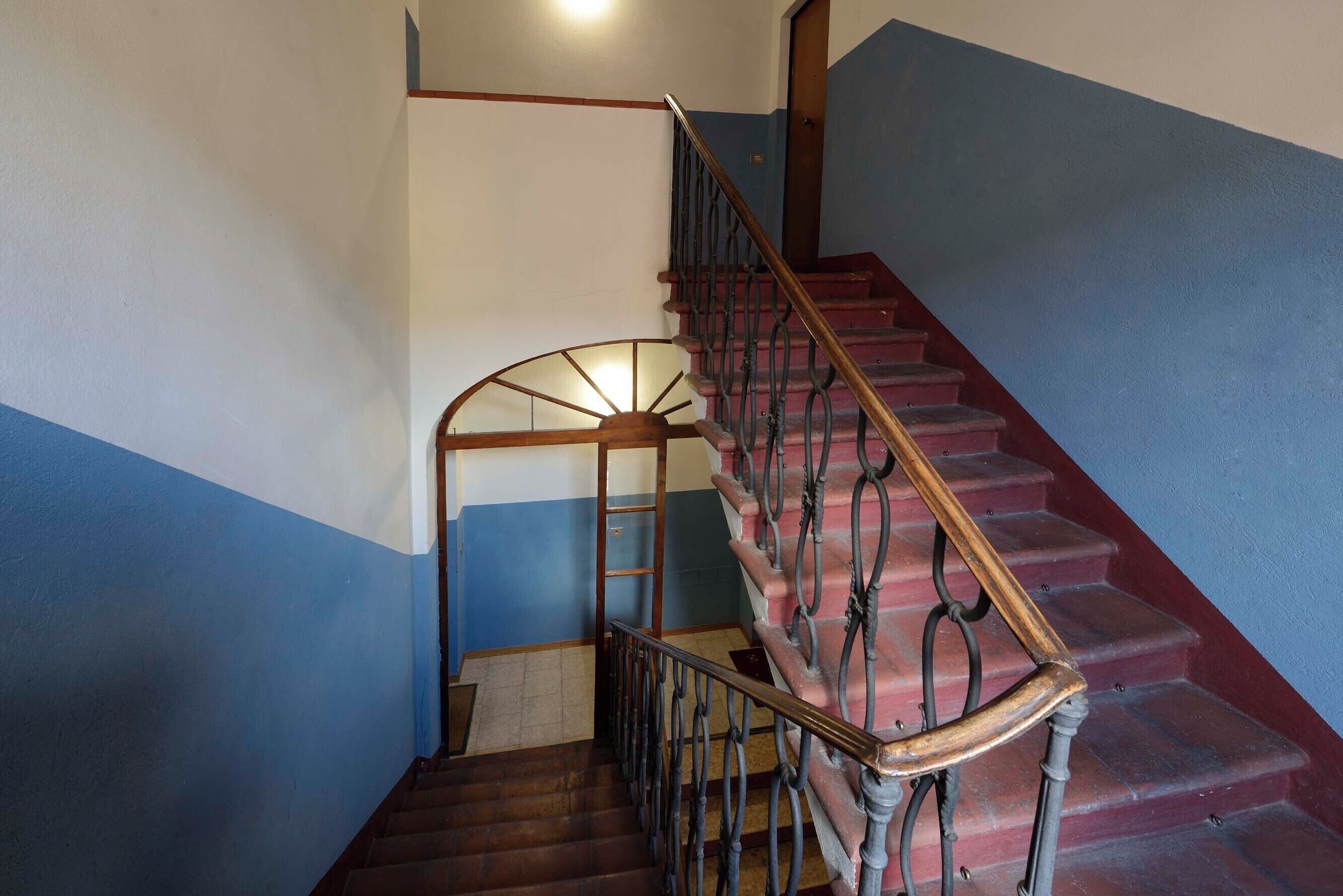 A staircase with a wooden handrail and metal balusters, leading to an upper floor.