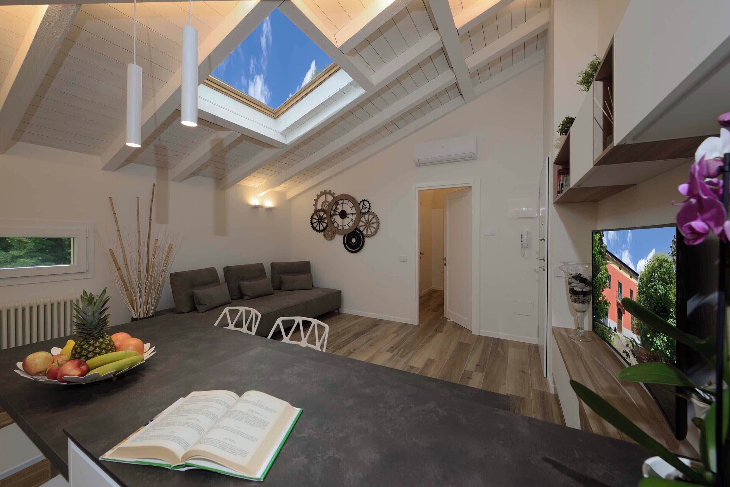 Eine moderne Küche mit Dachfenster, ein Essbereich mit einer Couch und Blick ins Freie.