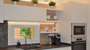A modern kitchen with a built-in window, a coffee maker, and a microwave. - GRENIER BLANC ELEGANT AND NEW ATTIC (San Pietro In Casale)