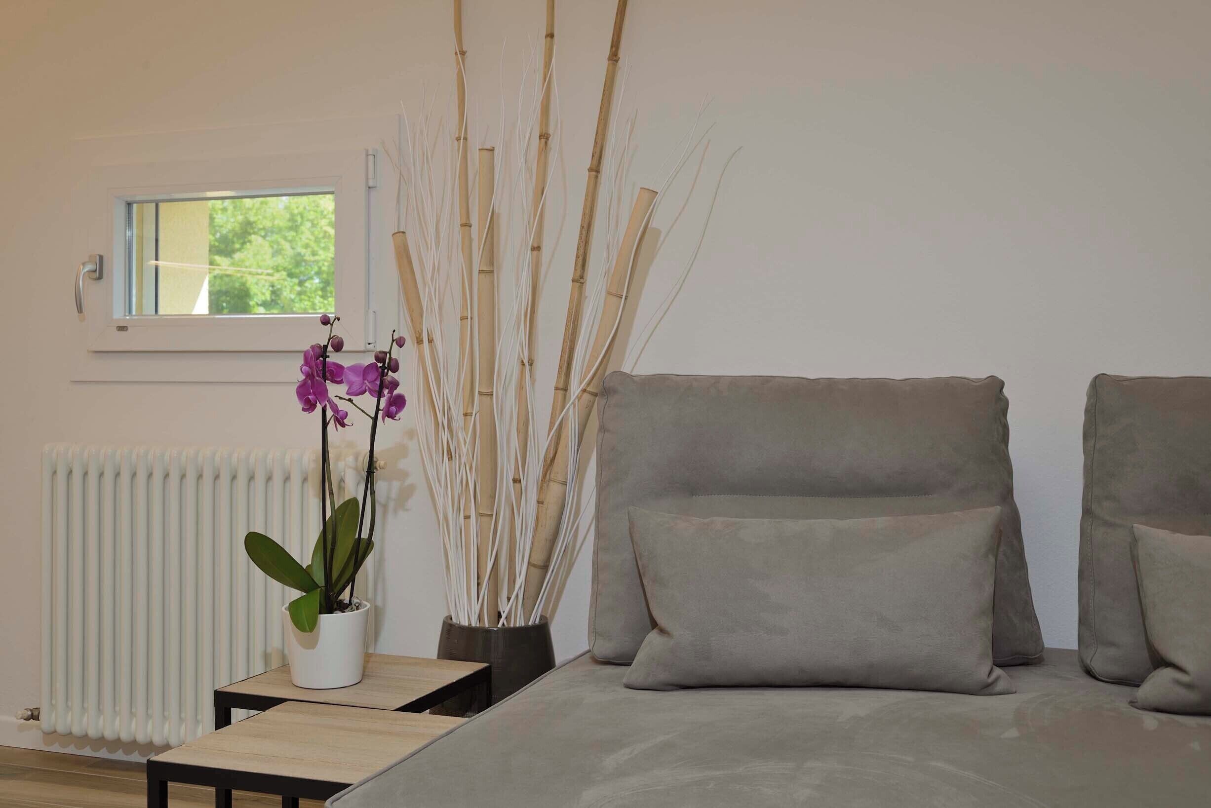 Una camera da letto moderna con un letto, un tavolino, un'orchidea in vaso e steli di bambù.