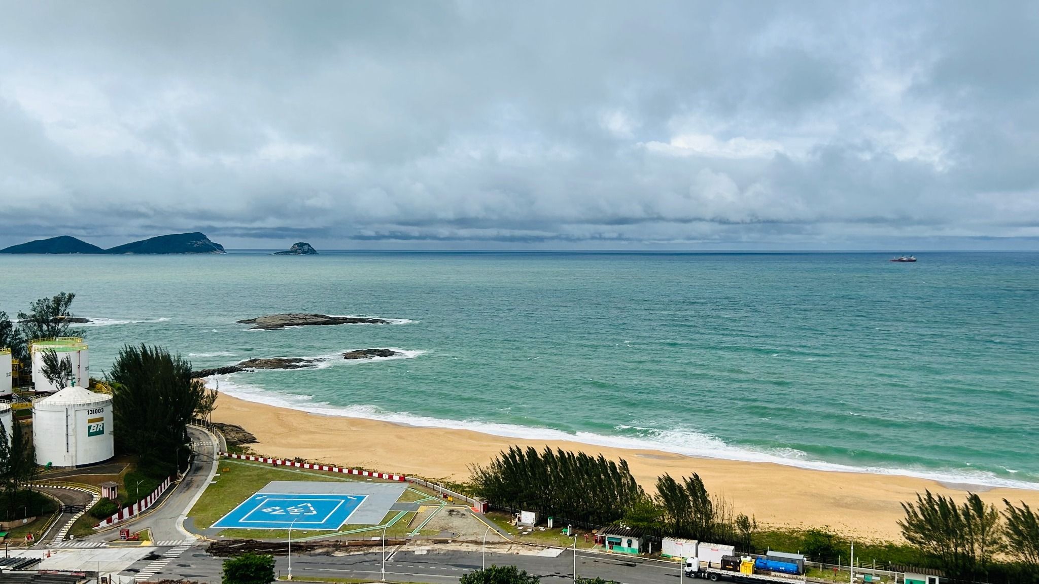 A beach with a parking area and a view of the ocean.