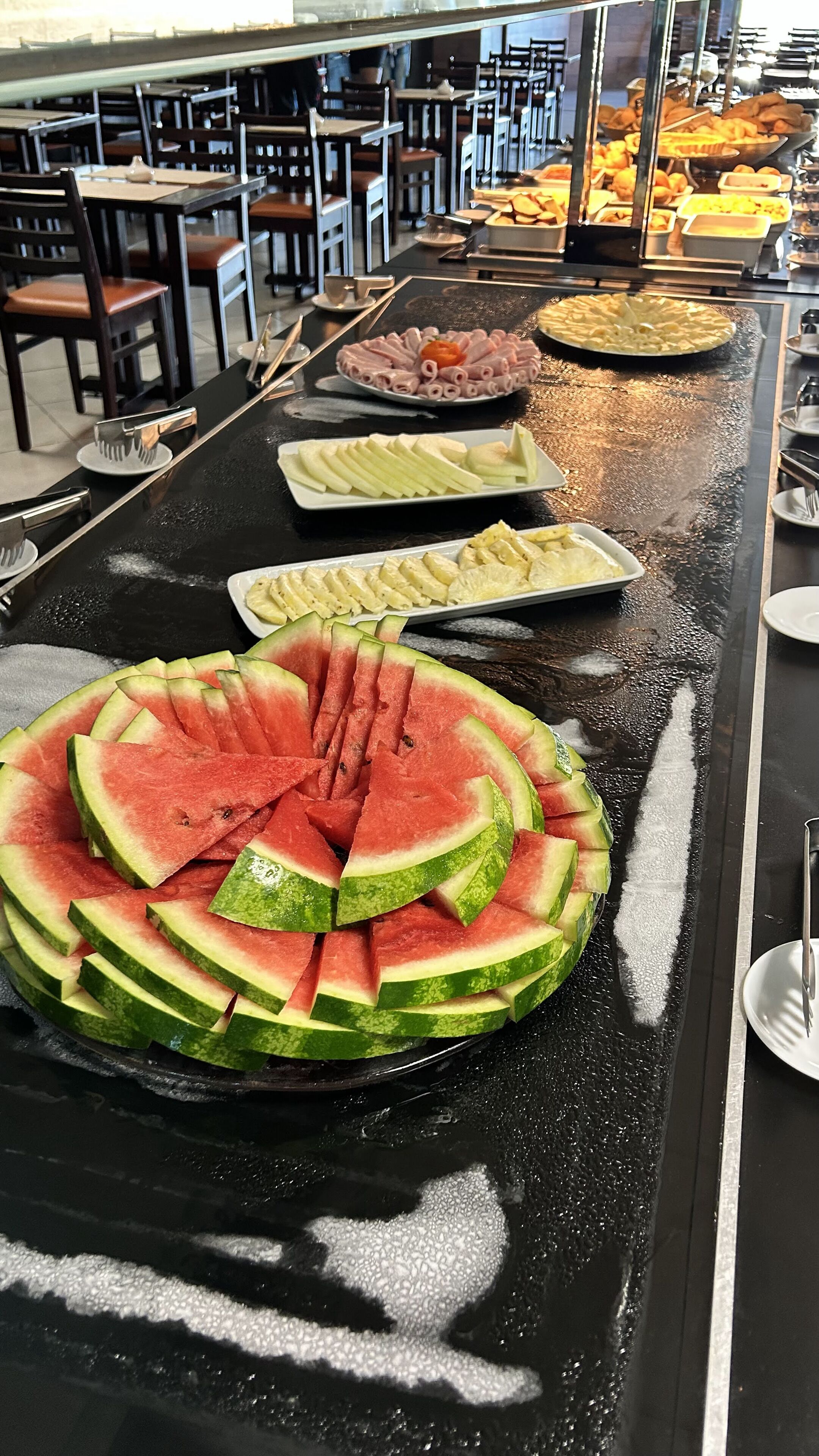 A buffet with various food items including watermelon slices, ham, and other dishes.
