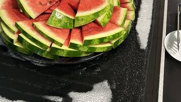 A buffet with various food items including watermelon slices, ham, and other dishes.