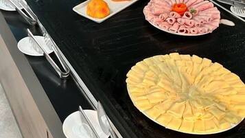 Un bufé con diversos platos, incluyendo sandía, pan y una amplia variedad de frutas.
