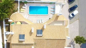 Eine Luftaufnahme eines Resorts mit Schwimmbad, Liegestühlen und einem Parkplatz.