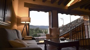 A cozy room with a sofa, a chair, a lamp, and a view of a mountainous landscape through a window. - La Casa del Guarda, an exclusive rural house 4* (Sotosalbos)