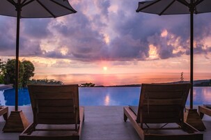 Una piscina al aire libre, sombrillas, sillones reclinables de piscina