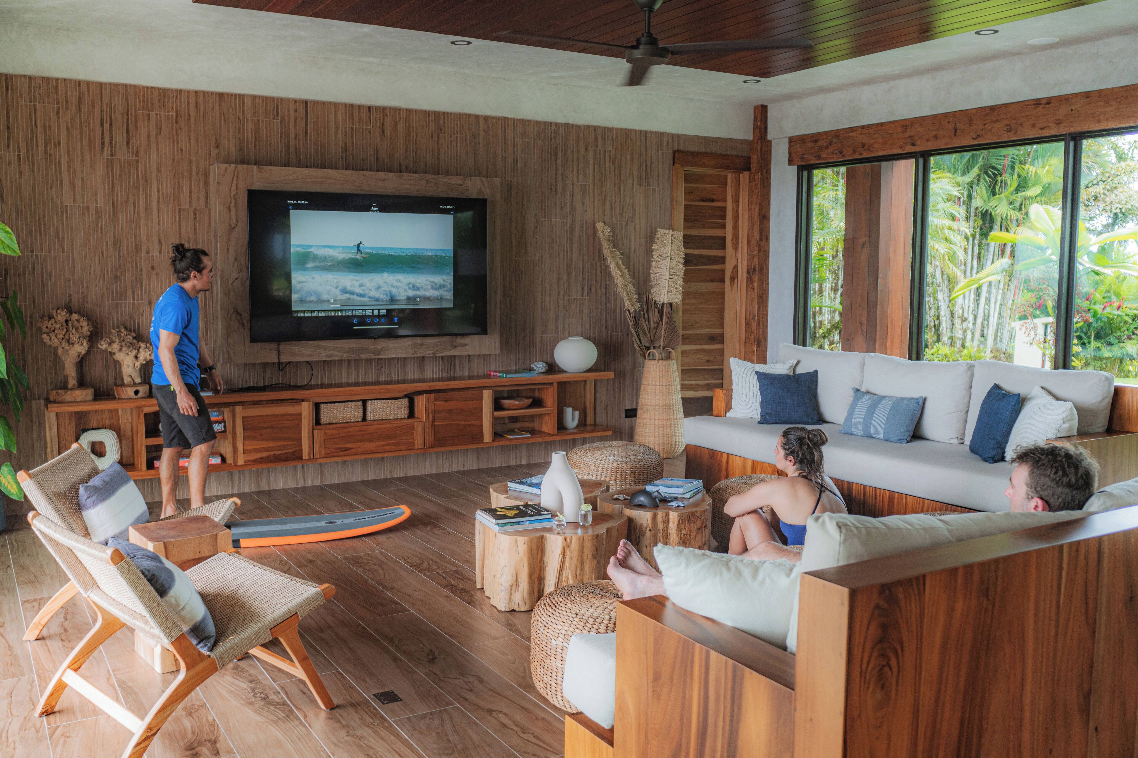 A modern living room with a large TV, wooden furniture, and a view of the outdoors.