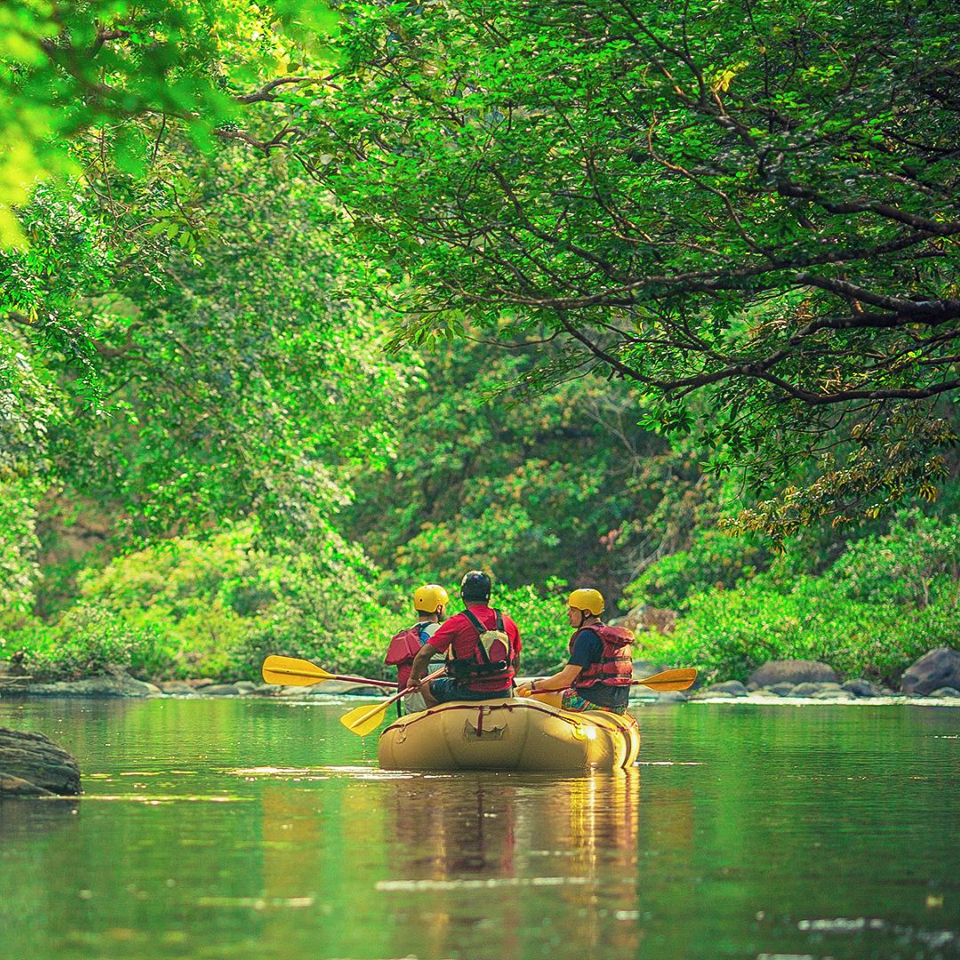 Un grupo de personas en una balsa flotando en un río tranquilo rodeado de vegetación densa.