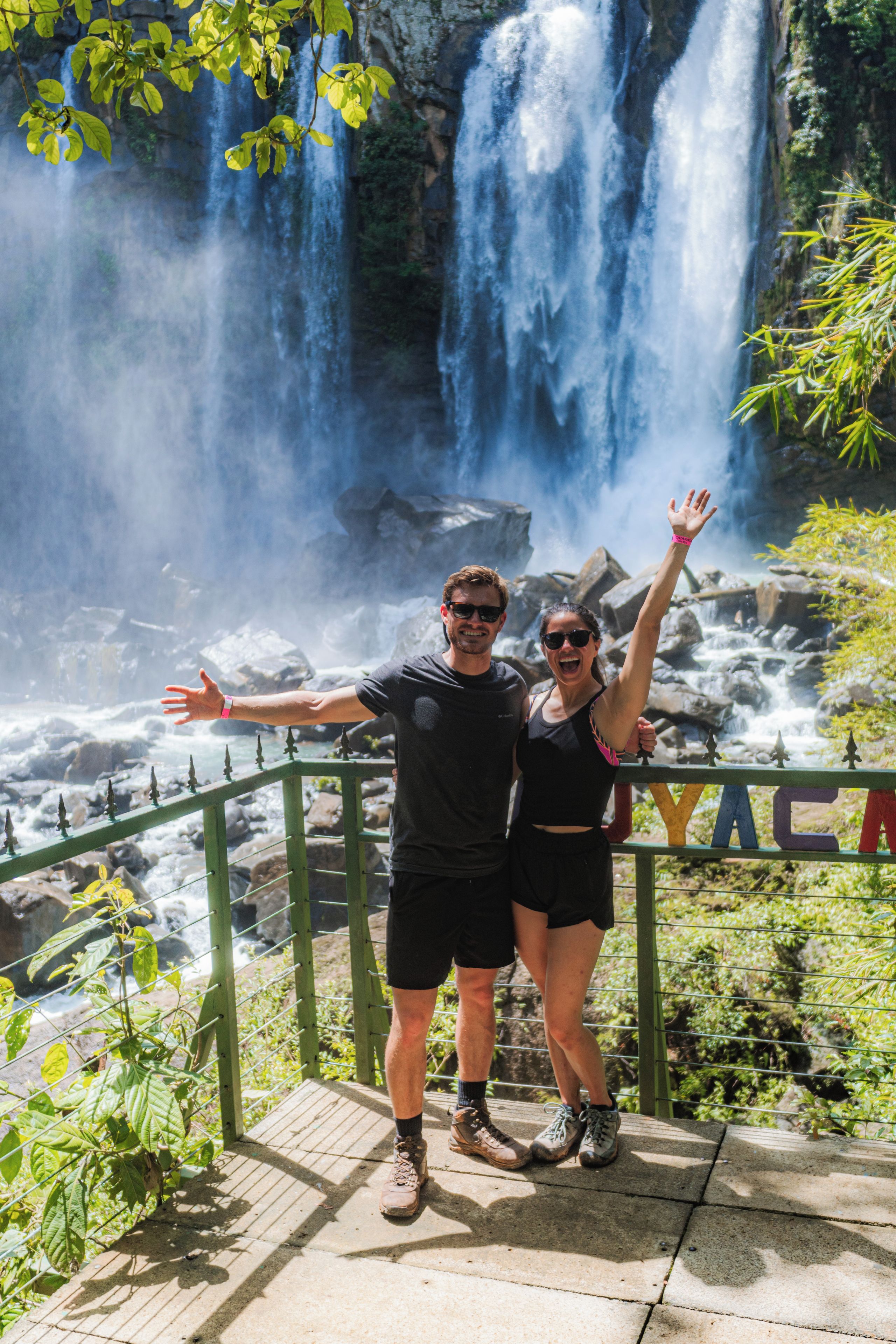 A couple standing on a viewing platform with a waterfall in the background.