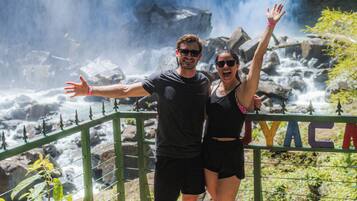 A couple standing on a viewing platform with a waterfall in the background.