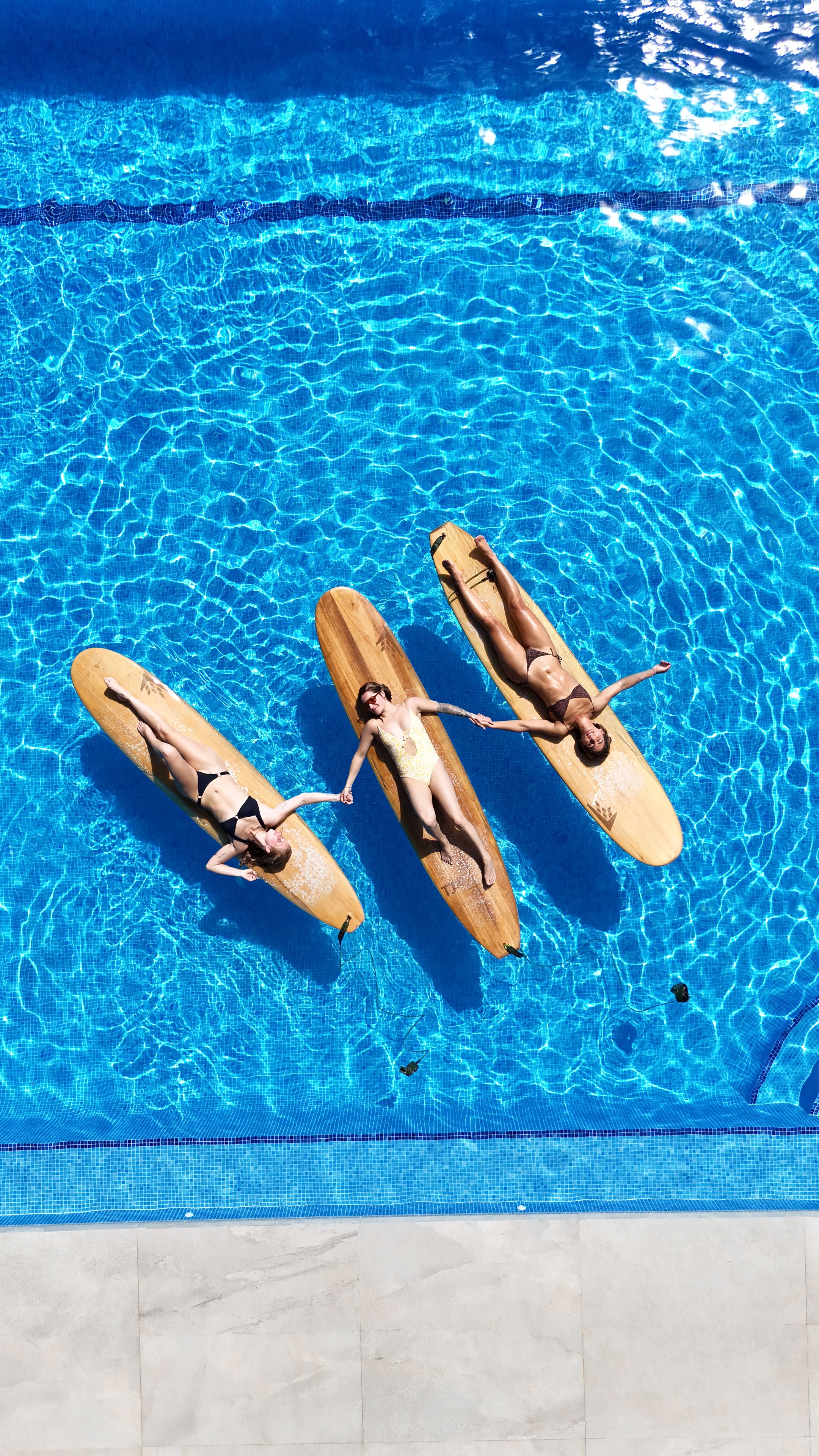 En klarblå pool med tre flytande träplattformar.