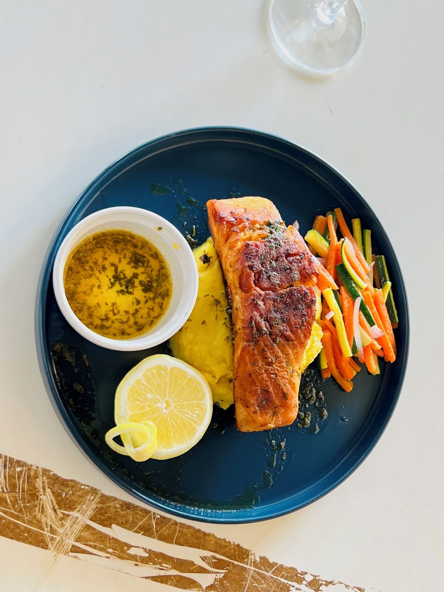 Un plato con salmón a la parrilla, puré de papas y verduras al vapor.