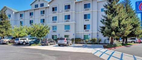 A multi-story hotel with a parking lot and several vehicles.