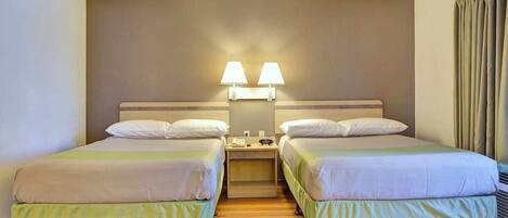A hotel room with two beds, a nightstand, and a wall-mounted lamp.