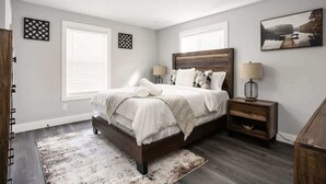 A bedroom with a bed, two bedside tables, a rug, and a painting on the wall. - Heart of Indy | Sleeps 6 | Modern Home (Indianapolis)