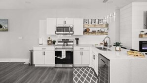 A modern kitchen with white cabinetry, stainless steel appliances, and a built-in oven. - Heart of Indy | Sleeps 6 | Modern Home (Indianapolis)