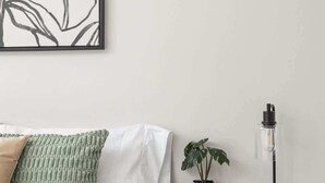 A bedroom with a bed, a nightstand with a lamp, a potted plant, and a framed artwork on the wall. - Downtown Access | 3BR Ranch Retreat with Fire-Pit (Indianapolis)