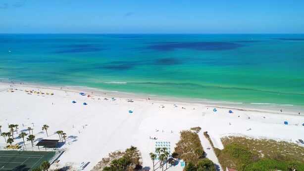 A beach with white sand, clear turquoise water, and a few umbrellas. - Steps to Siesta Key Beach! We offer 3-night rentals! Beach gear included! (Sarasota)