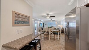 A kitchen with a granite countertop, a refrigerator, a dining area with a table and chairs, and a ceiling fan. - Steps to Siesta Key Beach! We offer 3-night rentals! Beach gear included! (Sarasota)