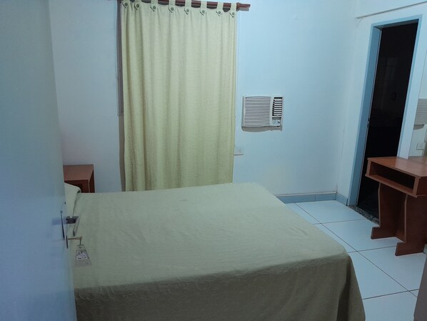 A room with a bed, a curtain, a wall-mounted air conditioner, a door, and a small table. - Hotel Paname (Buenos Aires)